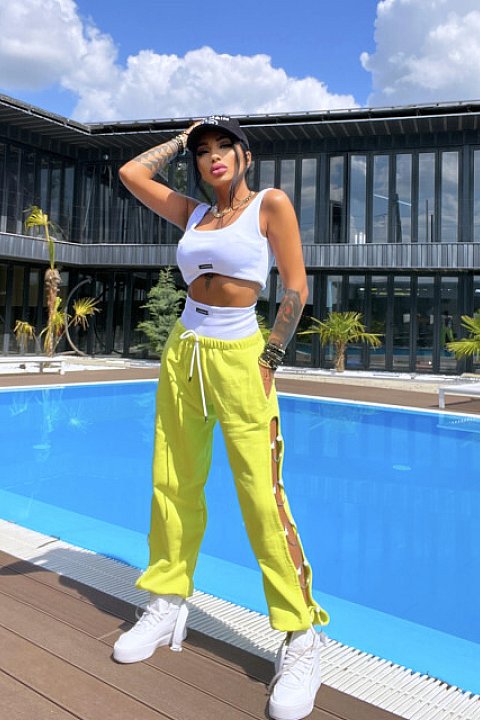 3-piece casual set, consisting of long yellow trousers with elastic at the ankles, and side cuts accessorized with silver hoops, white bustiers and briefs.