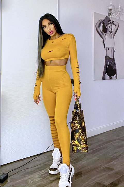 Mustard yellow 2-piece set, consisting of a waist-length blouse with multiple cuts on the sleeves and high-waisted shaped trousers.