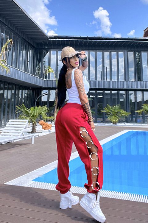 3-piece, casual set, consisting of long red trousers with elastic at the ankles, and side cuts accessorized with silver hoops, white bustier and briefs.
